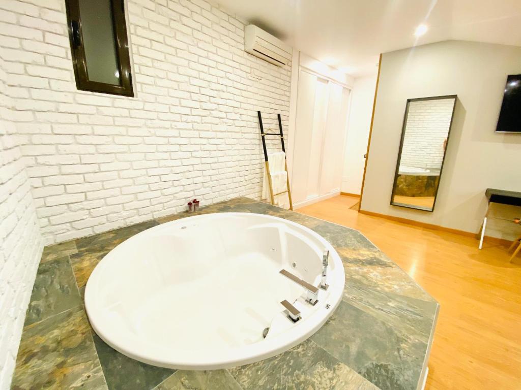 ein Badezimmer mit einer weißen Ziegelwand und einem Waschbecken in der Unterkunft SUITE SORPRESA VuT LA TABERNA in Arenas de San Pedro