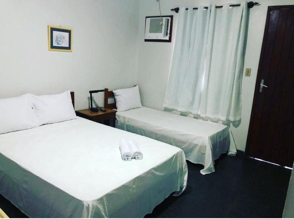 a room with two beds and a window at Pousada da Jaqueira - EPP in Rio das Ostras