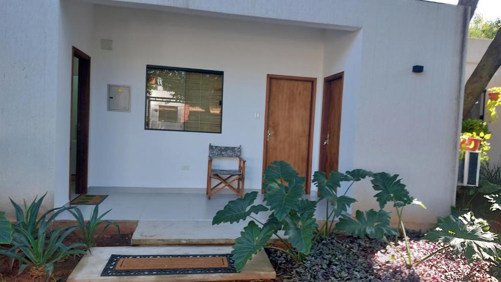 une maison blanche avec une porte en bois et une chaise dans l'établissement Casa de Mia, à Asuncion