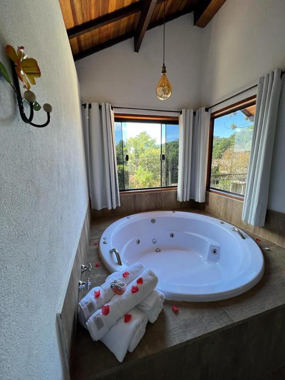 a bathroom with a large tub with towels on the floor at Chalés Cantinho do Sossego in Monte Verde