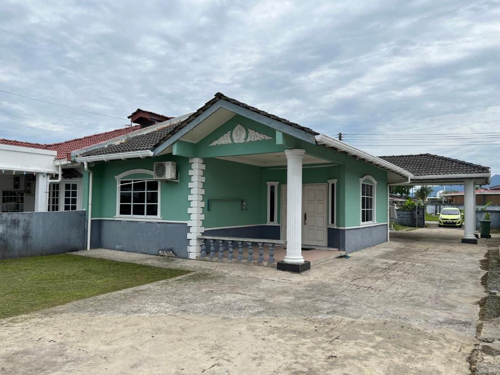 a green house with a driveway in front of it at Hanif Homestay in Kuching