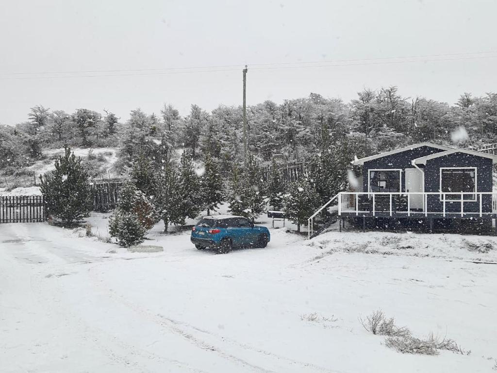 un coche azul aparcado en un patio cubierto de nieve en Cabaña Nothofagus PUQ, en Punta Arenas