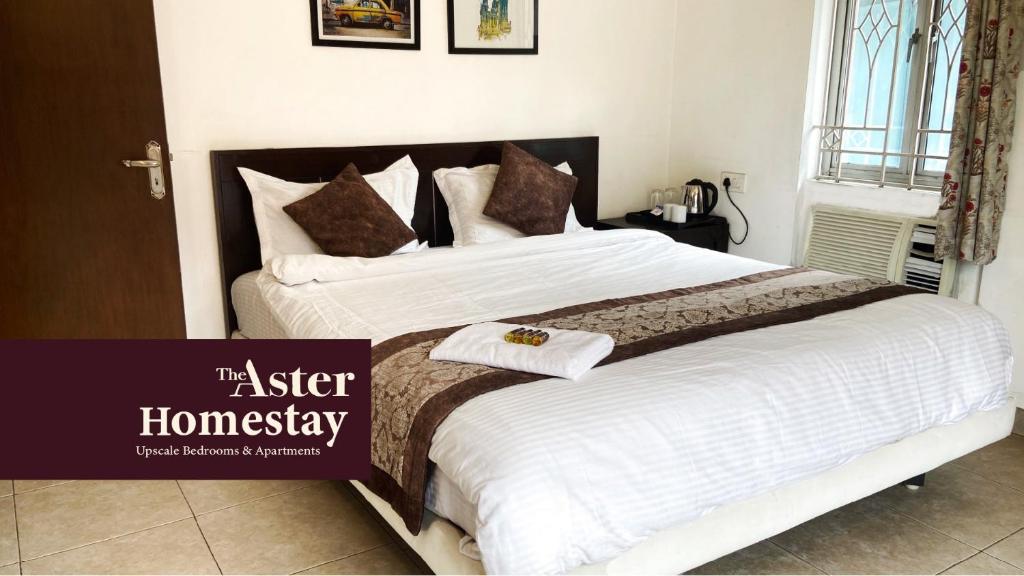 een slaapkamer met een groot bed met witte lakens en bruine kussens bij The Aster Homestay - Bedrooms & Apartments in Calcutta