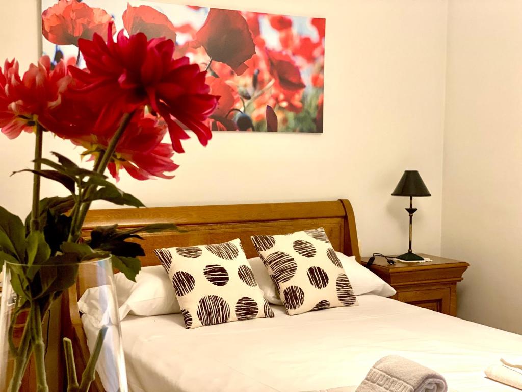 a bedroom with a bed with a vase with red flowers at Housingleón - Tu casa en León in León