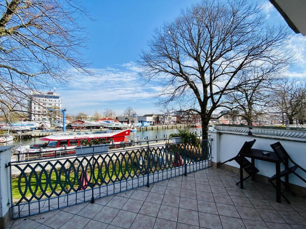 una panchina su un balcone affacciato su un fiume con barche di Doppelzimmer Lunch, direkt am Alten Strom a Warnemünde