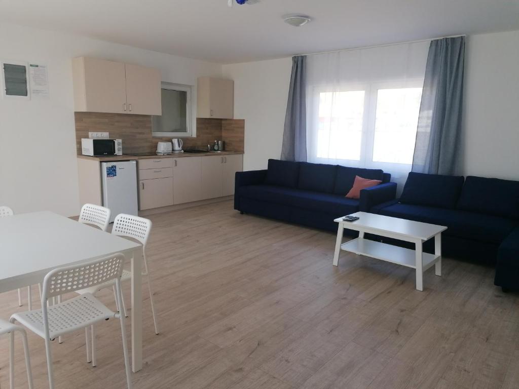 - un salon avec un canapé bleu et une table dans l'établissement Sóstói Strand Apartmanház, à Siófok