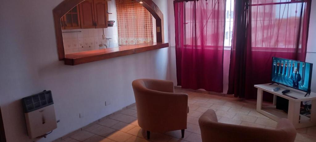 een woonkamer met een televisie en een bureau met stoelen bij Departamento Familiar Mendoza City in Mendoza