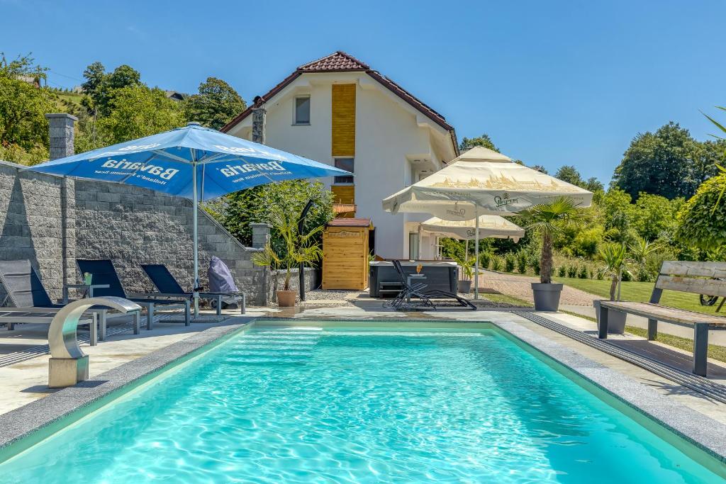 a swimming pool with an umbrella and chairs and a house at Pool & Whirlpool Art Villas in Trebnje
