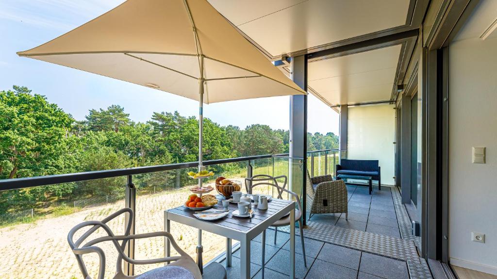 une terrasse avec une table, des chaises et un parasol dans l'établissement Strandurlaub Rügen "Lütt Oskar", à Binz