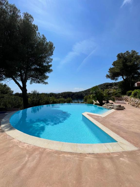 uma piscina azul com uma árvore ao fundo em Appartement avec magnifique vue Piscine Lac et Mer Ref RDL 113 em Saint-Raphaël