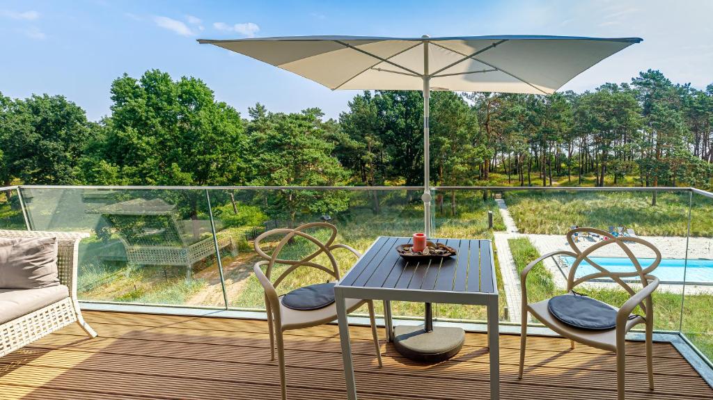 einen Tisch und Stühle auf einer Terrasse mit einem Sonnenschirm in der Unterkunft Strandurlaub Rügen "Lütt Matten" in Binz