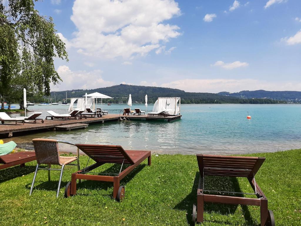 two chairs and a dock with a boat in the water at Ferienwohnung in Reifnitz am Wörthersee mit Seezugang in Reifnitz