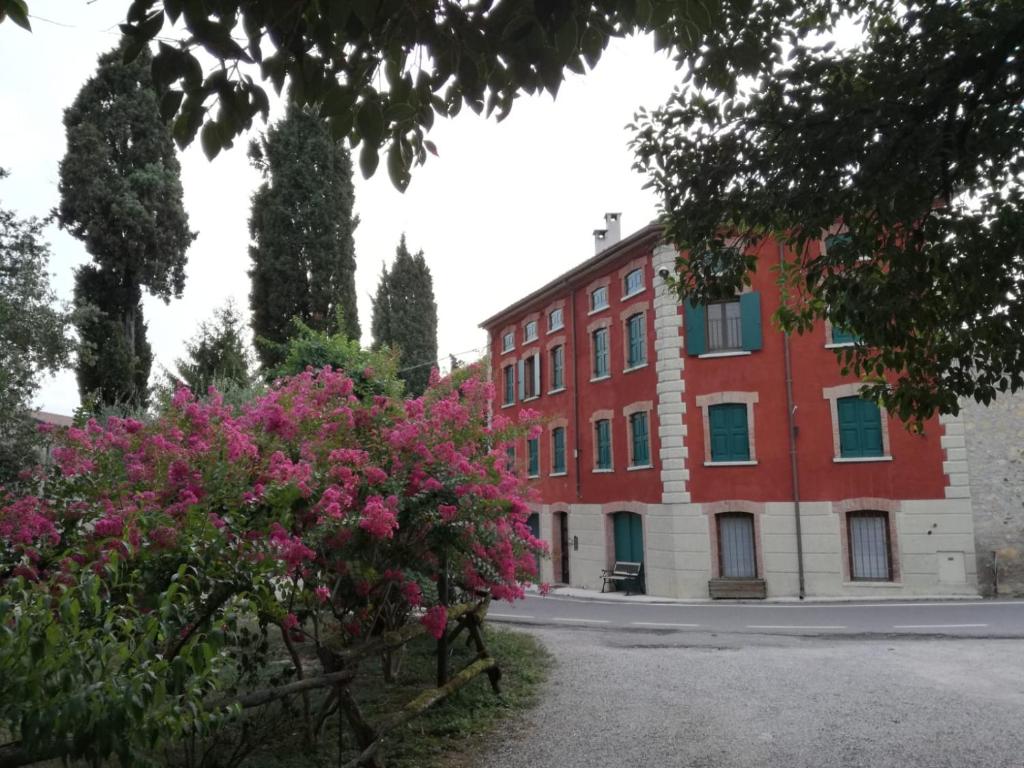 budynek z czerwonej cegły z różowymi kwiatami przed nim w obiekcie Maregnago Relais w mieście Marano di Valpolicella