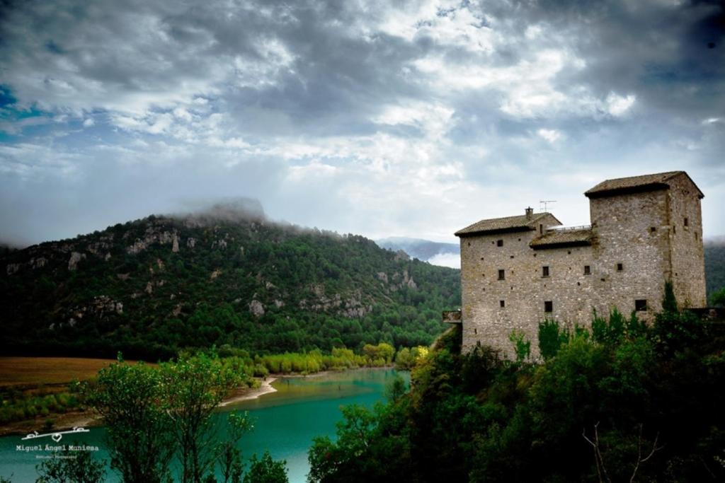 un viejo castillo en una colina junto a un río en Ligüerre Resort en Ligüerre de Cinca