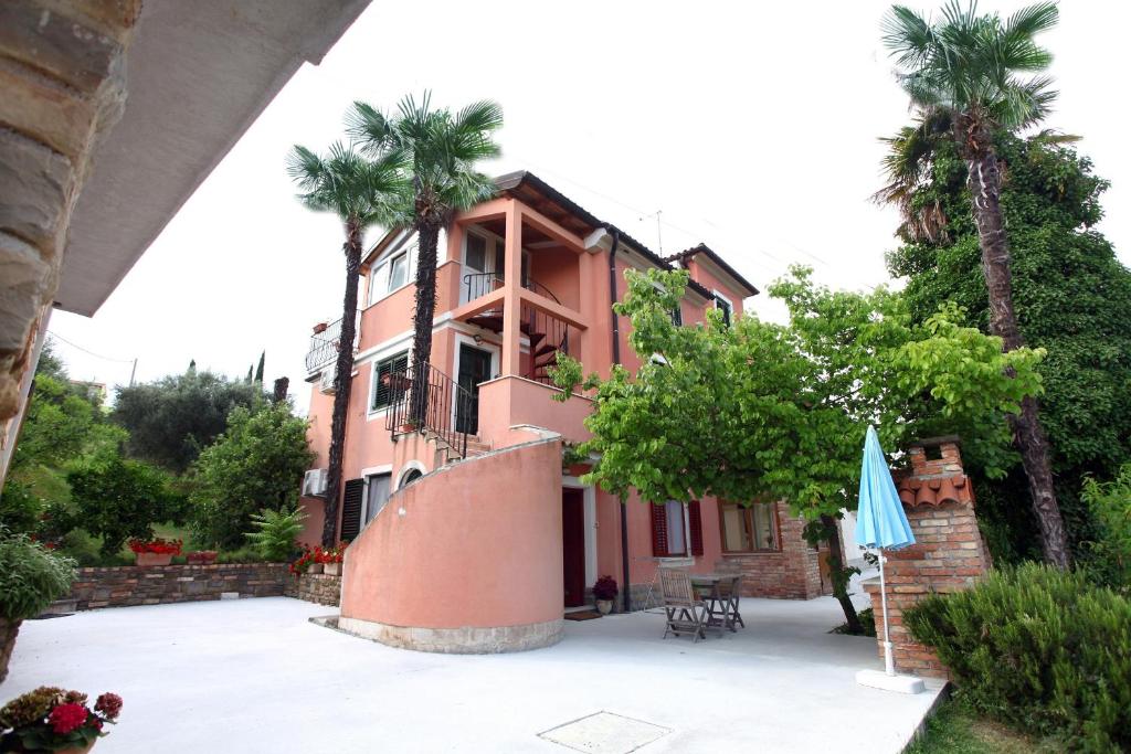 una casa rosa con palmeras delante en Apartment Roxor en Portorož