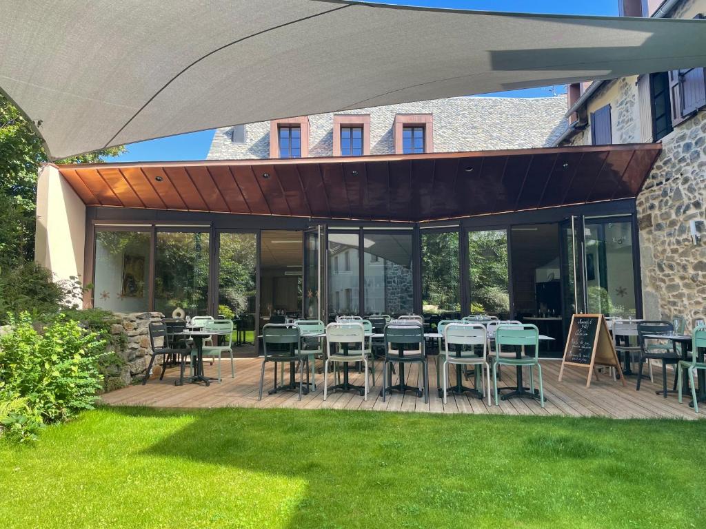 un patio con tavoli e sedie su un prato di Logis hôtel restaurant l'Argence a Sainte-Geneviève-sur-Argence