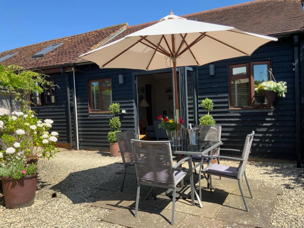 a table and chairs with an umbrella in front of a house at Beulah Cottage Annexe in Ashford