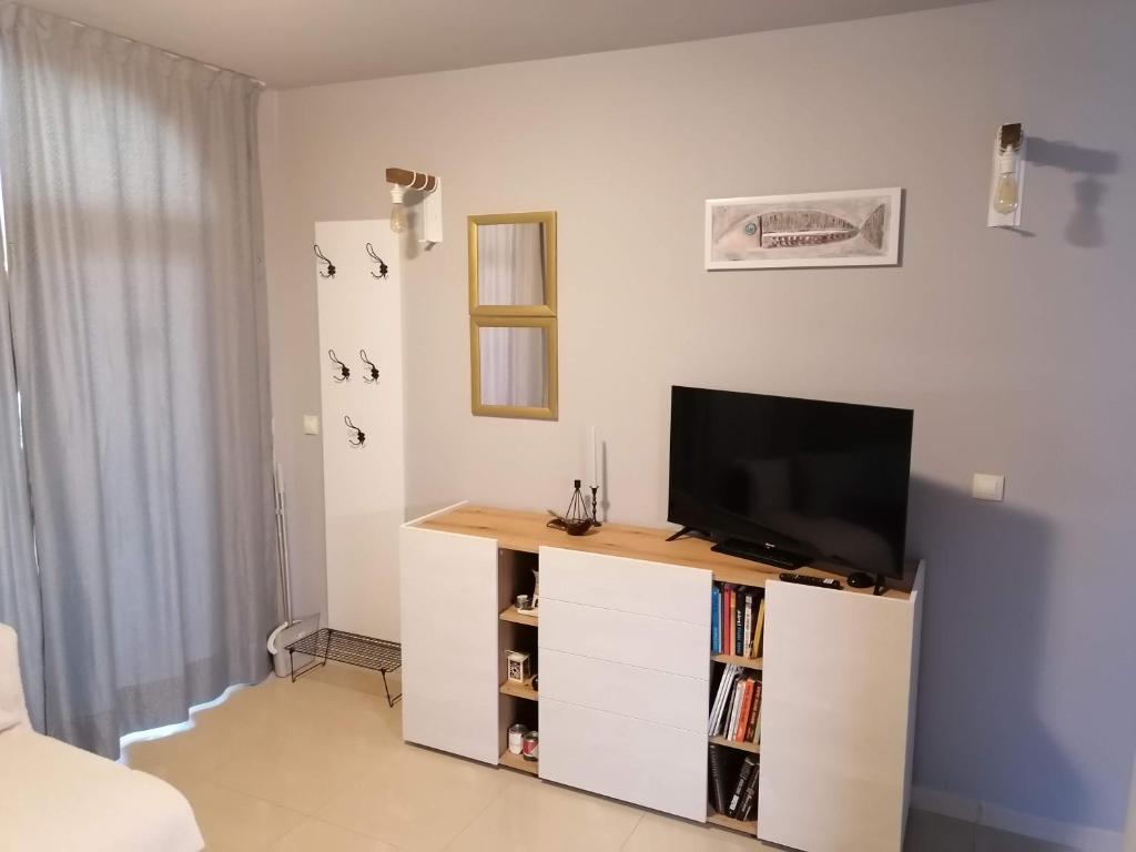 - un salon avec une télévision sur un meuble blanc dans l'établissement Casa do Farol - апартамент с басейн до плажа, à Tchernomorets