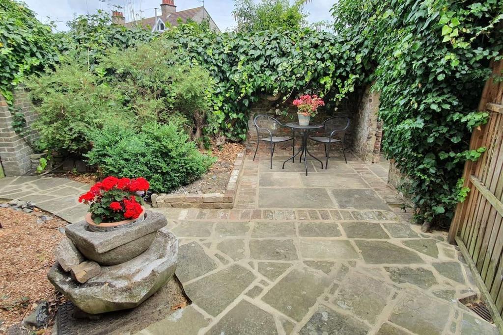 a patio with a table and chairs and flowers at Beautiful 1 bedroom cottage with courtyard. in Kent