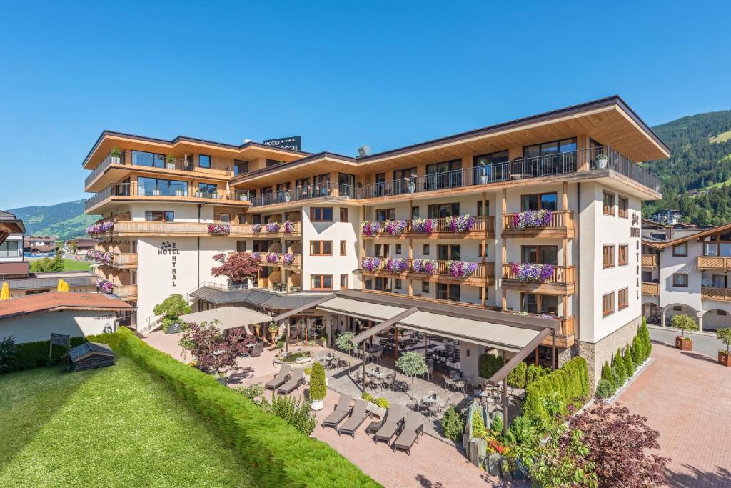 a hotel in the mountains with a patio and tables and chairs at Hotel Zentral ****superior in Kirchberg in Tirol