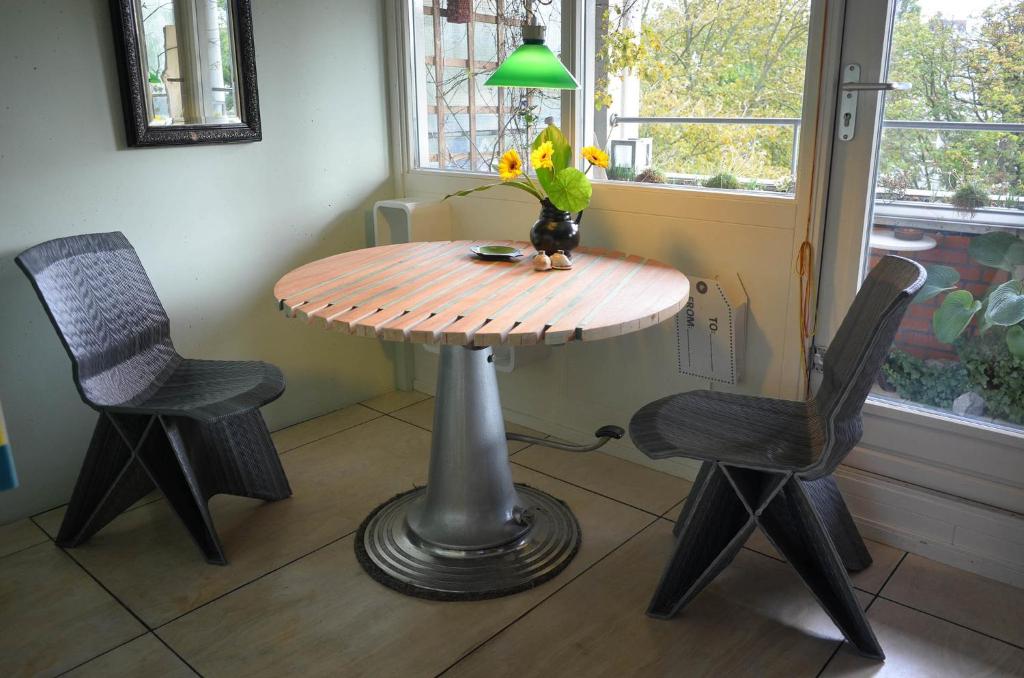 einen Tisch mit zwei Stühlen und eine Vase mit Blumen in der Unterkunft Treetop Apartment in Den Haag