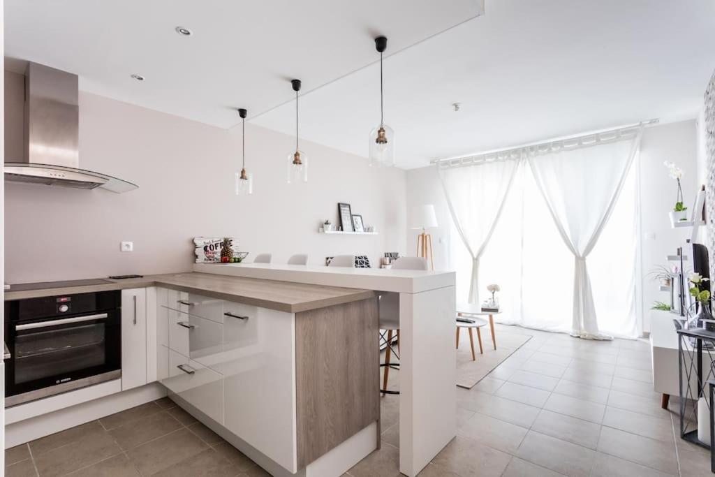 cocina blanca con encimera y fregadero en Appartement Le Patio - Stationnement privatif & Tram - proche Montpellier en Saint-Jean-de-Védas