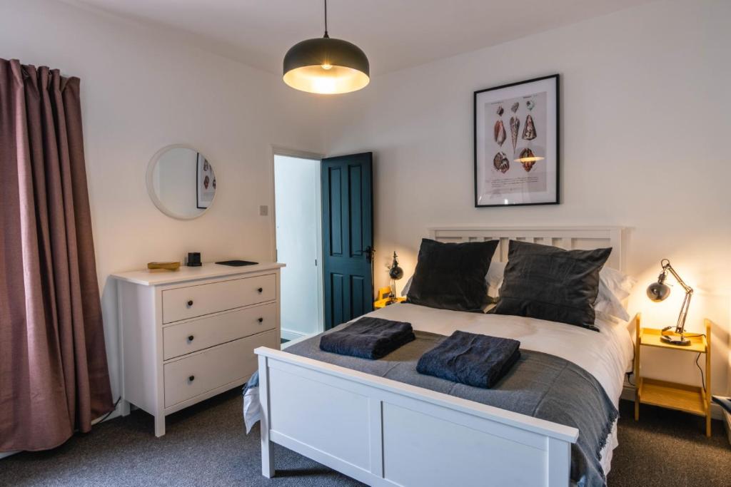 a bedroom with a white bed and a dresser at Newly refurbished Modern Stylish 2 Bedroom Cottage in Lowestoft