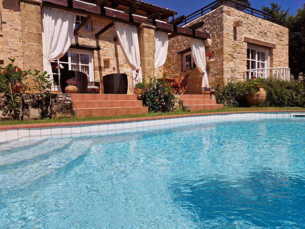 a large swimming pool in front of a house at Rock House's Villa Melody in Platanias
