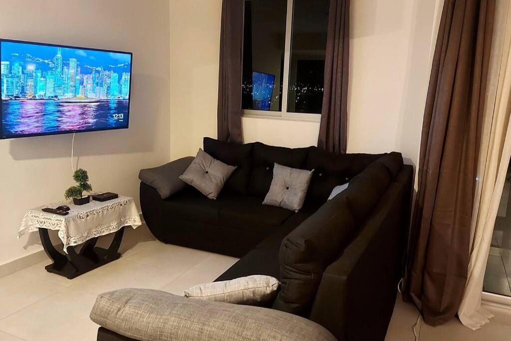 sala de estar con sofá negro y TV en Altamira Cozy apartment with amazing views, en Santo Domingo