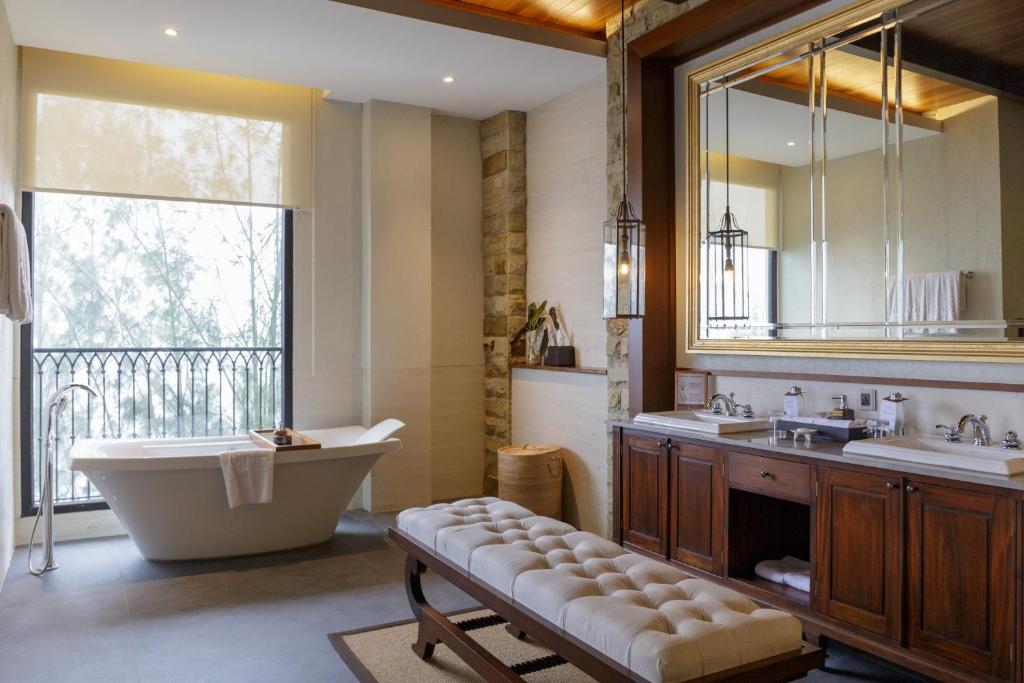 ein Badezimmer mit einer Badewanne, 2 Waschbecken und einem großen Spiegel in der Unterkunft Plataran Bromo in Ngadiwano