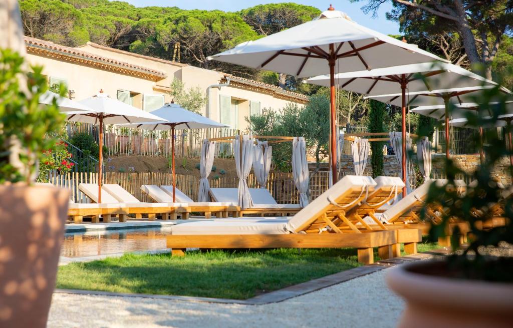 a group of chairs and umbrellas next to a pool at Hôtel L'Escalet in Ramatuelle