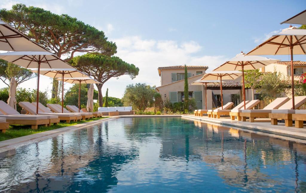 a swimming pool with lounge chairs and umbrellas at Hôtel L'Escalet in Ramatuelle