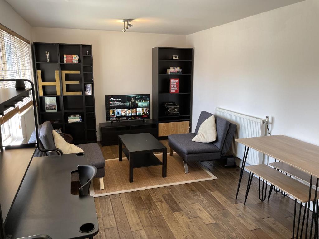 a living room with a table and a television at Beautiful apartment right off of Broadway Market in London