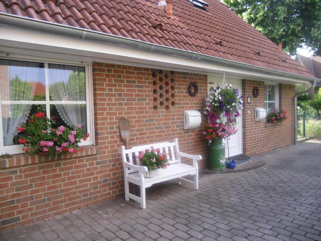 a brick house with two white benches and flowers at Lindensweet in Lindwedel