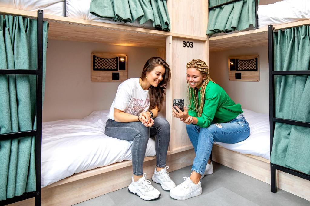two girls sitting on bunk beds in a dorm room at The Bee Hostel in Amsterdam