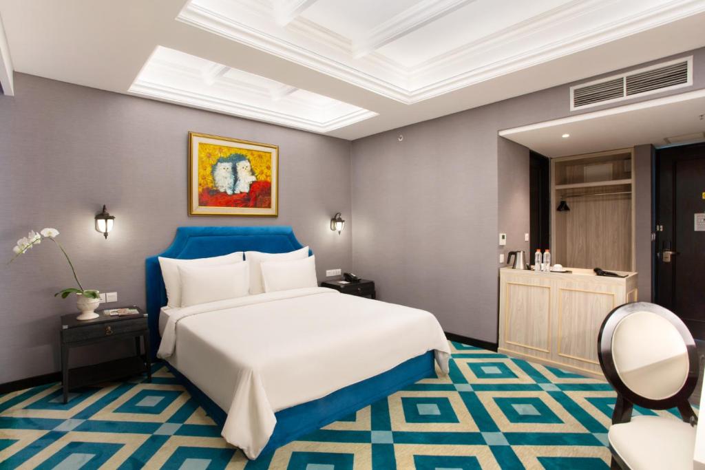 a bedroom with a large bed with a blue headboard at Hotel Des Indes Menteng in Jakarta