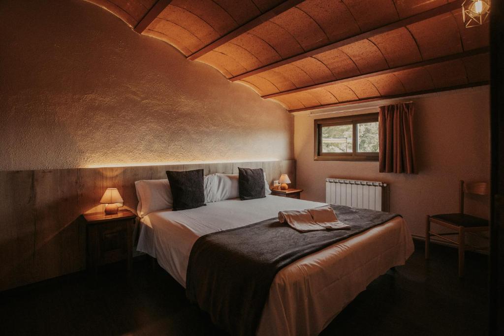 ein Schlafzimmer mit einem großen Bett in einem Zimmer mit Holzdecken in der Unterkunft Subirana Rural in Les Llosses