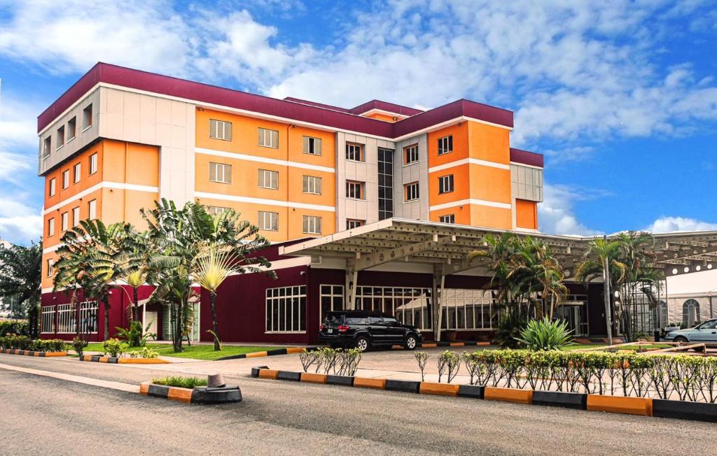 a building with a car parked in front of it at Heliconia Park Port Harcourt Hotel and Suites in Port Harcourt
