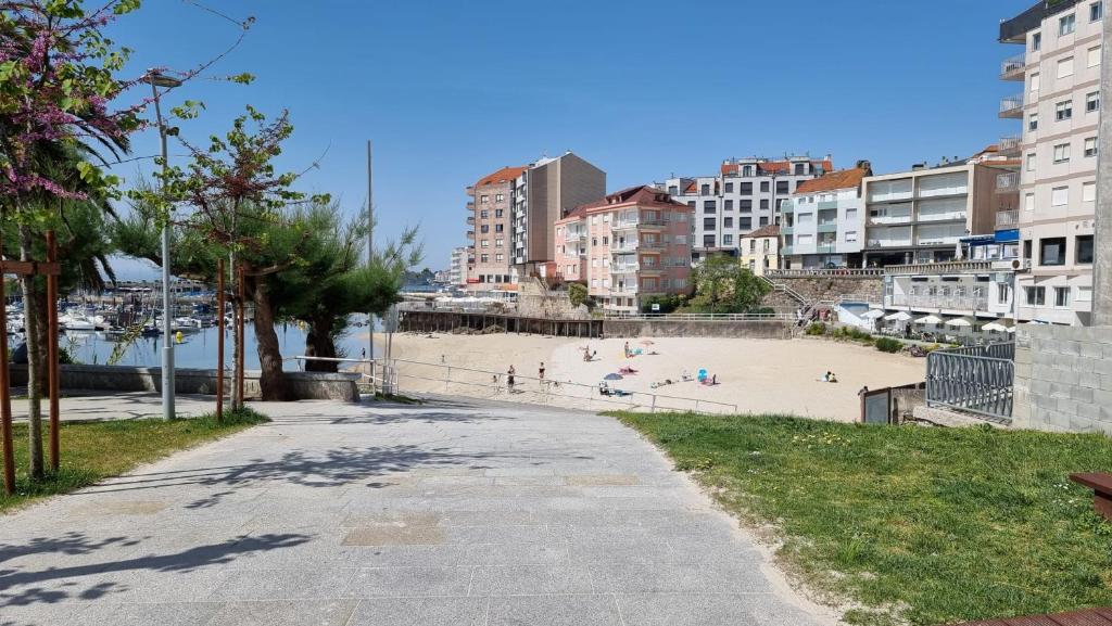 einen Strand mit Menschen auf dem Sand und Gebäuden in der Unterkunft Soleado piso 4 habit a pie de playa Sanxenxo in Sanxenxo
