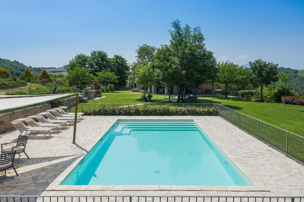 a swimming pool with chairs and a lawn at Casa Emanuela in Fermignano