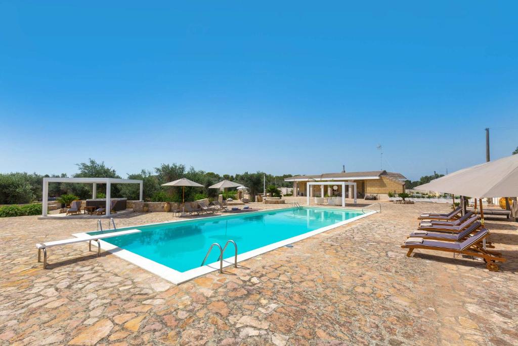 uma grande piscina com cadeiras e guarda-sóis em Villa Artesole by BarbarHouse em Oria