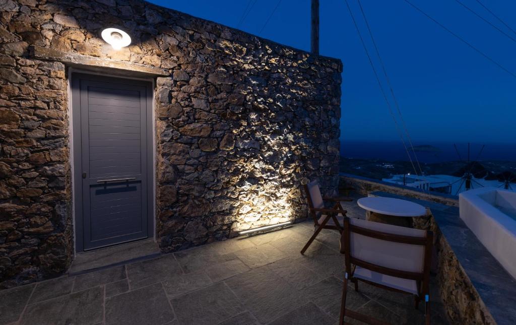 Habitación con pared de piedra, puerta y mesa. en Aelia House Serifos, en Serifos Chora