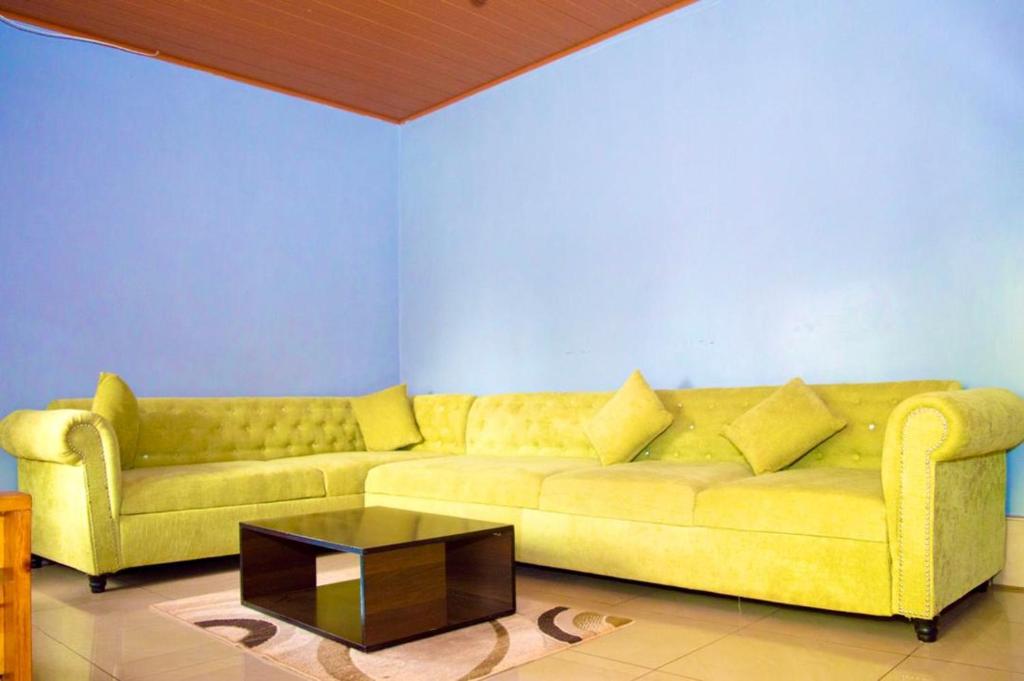 a living room with a yellow couch and a coffee table at INKINDI Property in Kigali