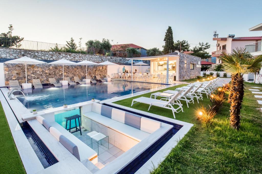 a swimming pool with chairs and tables next to a building at Epicentrum Suites in Limenaria