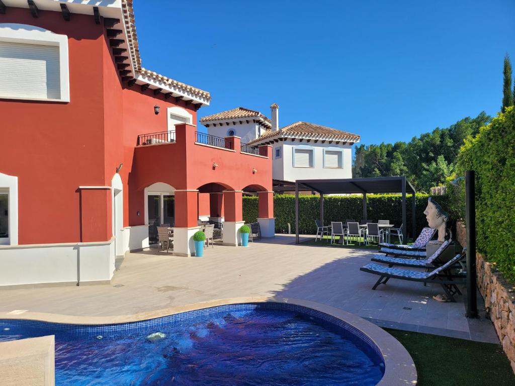 a woman sitting on a bench in front of a house at VILLA PALMITO Mar Menor Golf in Torre-Pacheco