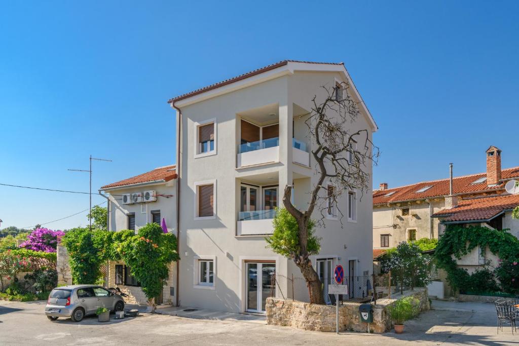 un edificio bianco con un'auto parcheggiata di fronte di MA Premantura Luxury Apartments Ferienwohnung - Premantura Pula Istria a Premantura