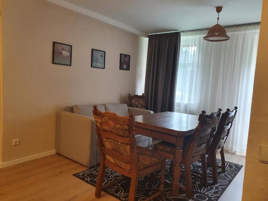 een eetkamer met een tafel en stoelen en een bank bij Laukdvaris in Laukžemė