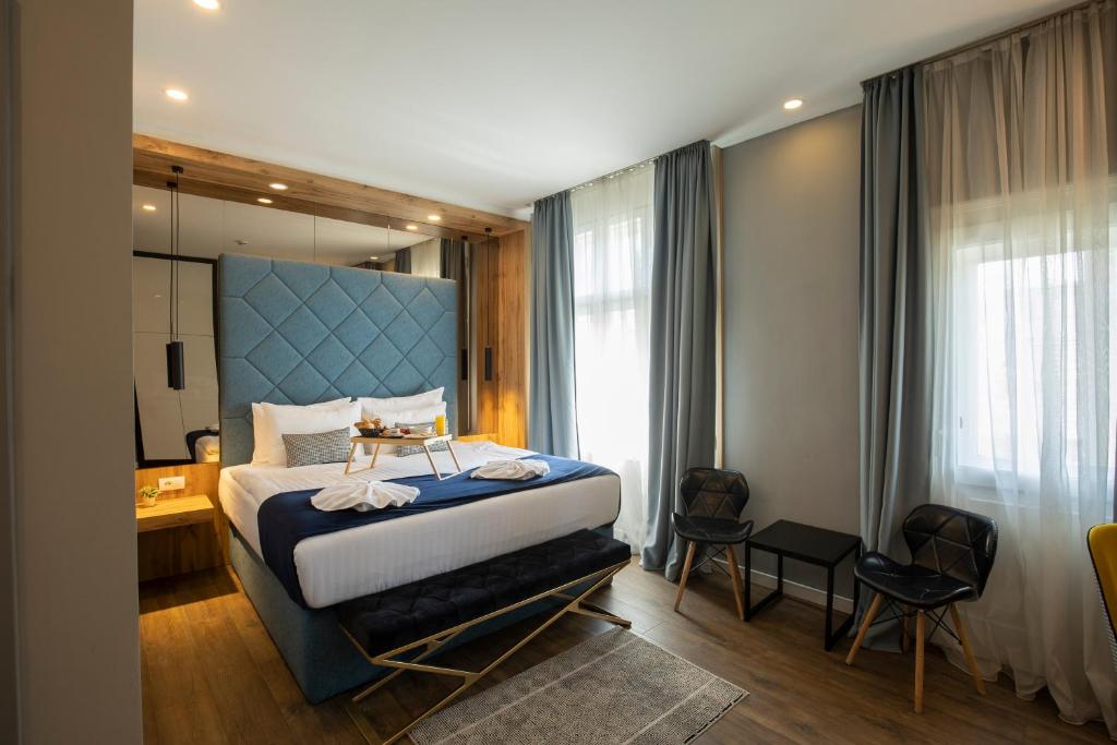 a bedroom with a large bed with a blue headboard at Nobel Gallery Hotel in Belgrade