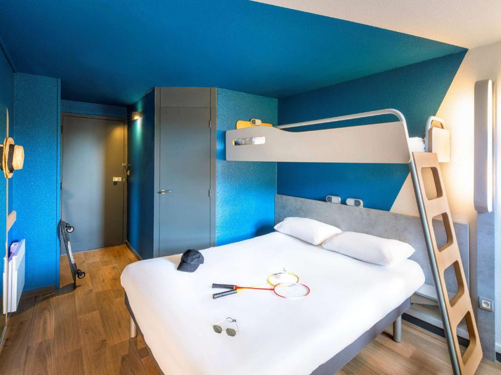 Schlafzimmer mit einem Bett mit blauer Wand in der Unterkunft ibis budget Grenoble Voreppe in Voreppe