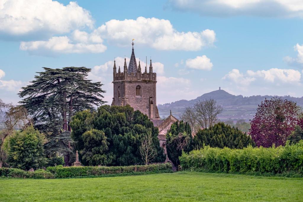 an old building with a tower in a field at The Little Cottage - Peaceful, Dog Friendly Cottage in 5 Acres in Glastonbury